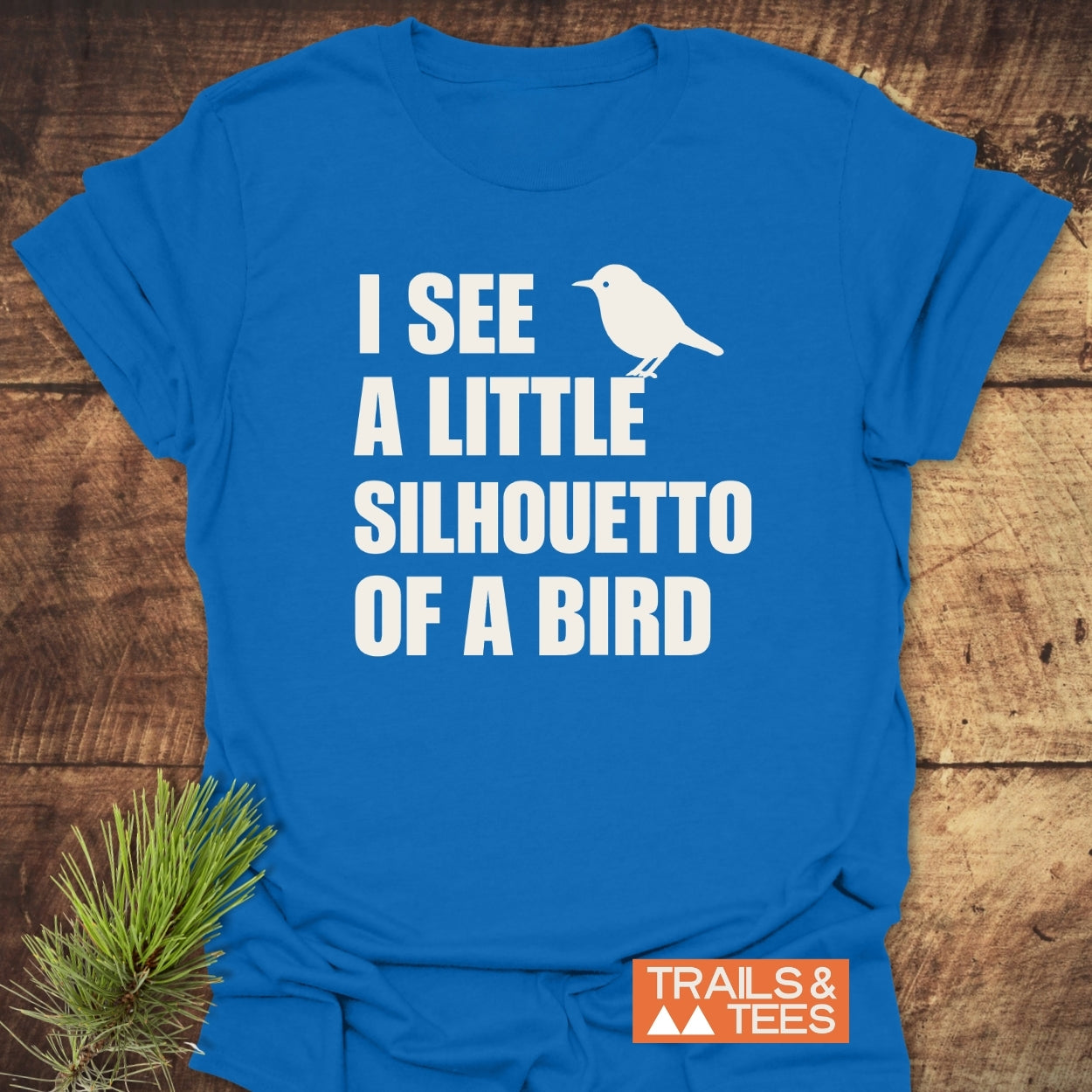 Silhouetto Of A Bird Funny Softstyle T-Shirt featuring bold white text and bird silhouette on a bright-blue, lightweight tee. Displays TRAILS & TEES logo, emphasizing casual comfort and modern fit.