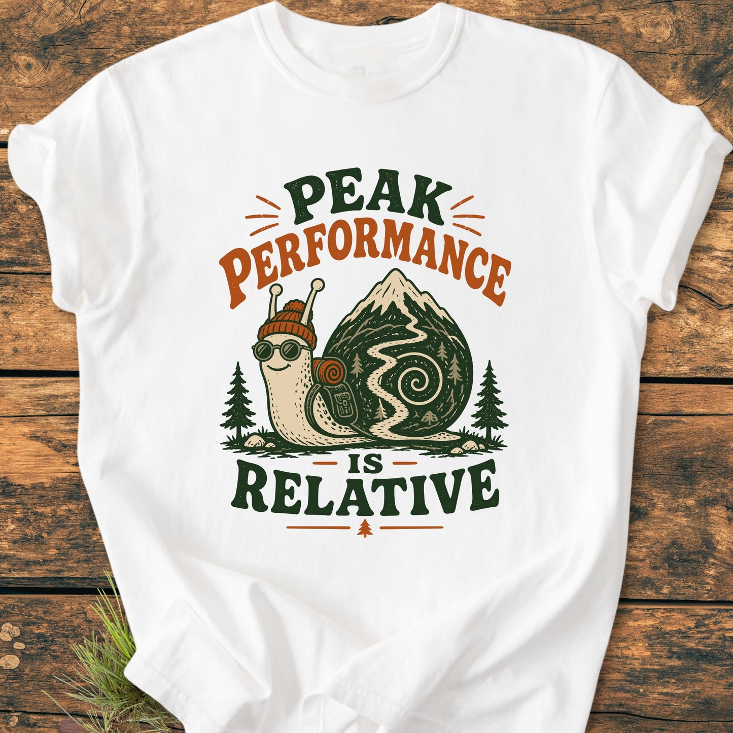 Peak Performance Is Relative - Vintage Wash Tee: White T-shirt with a cartoon snail in hiking gear on a mountain trail, featuring the slogan above and below, ideal for leisurely adventurers.