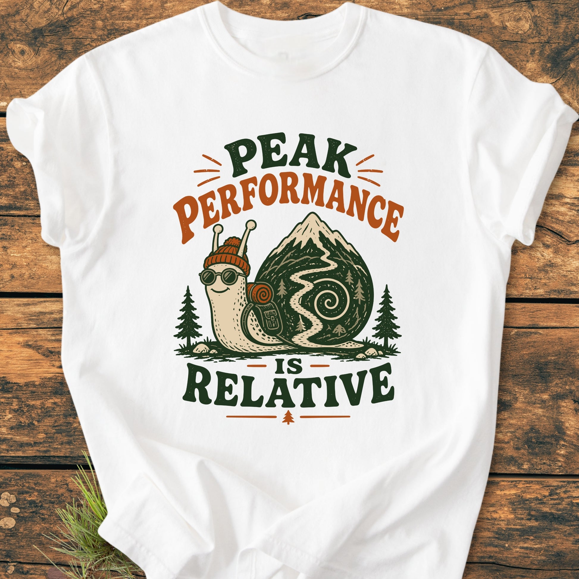 Peak Performance Is Relative - Vintage Wash Tee: White T-shirt with a cartoon snail in hiking gear on a mountain trail, featuring the slogan above and below, ideal for leisurely adventurers.