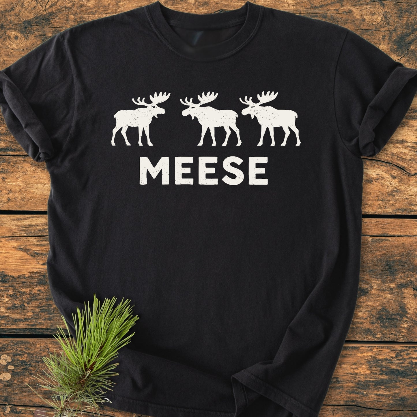 Black T-shirt featuring three white moose silhouettes above MEESE, humorously crafted for moose enthusiasts. The Meese - Vintage Wash Tee embodies outdoor humor and casual, everyday wear.