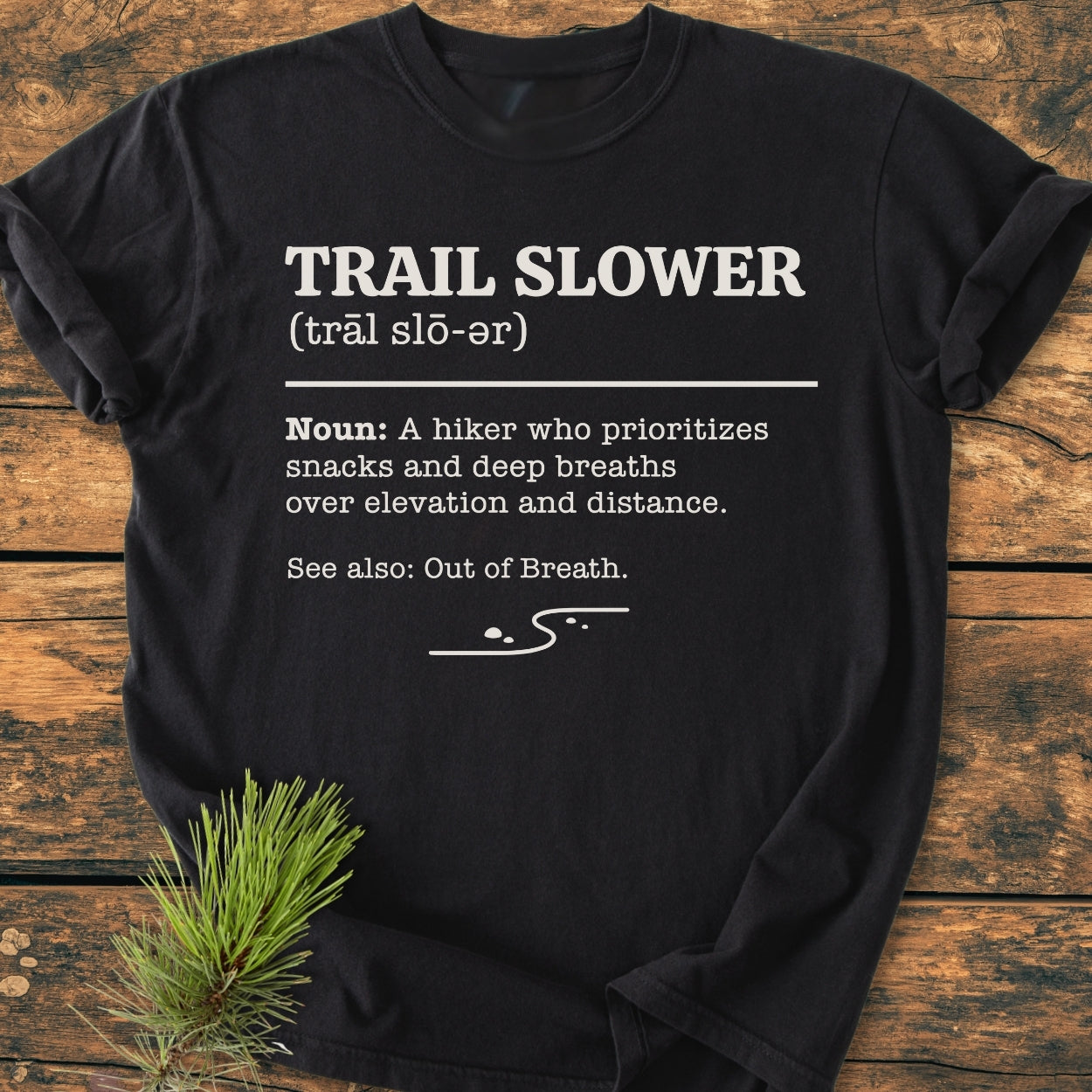 Trail Slower Dictionary - Vintage Wash Tee: Black T-shirt on rustic wood with playful 'Trail Slower' dictionary entry and line-art trail graphic, ideal for leisurely hikers valuing comfort and style.
