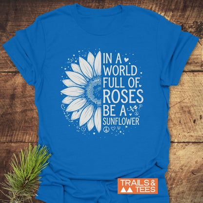Be A Sunflower Softstyle T-Shirt features a white half-sunflower graphic with hearts and swirls on a royal-blue tee, alongside the phrase promoting individuality and positivity.