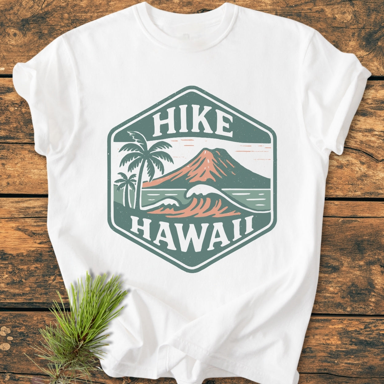 Hike Hawaii - Vintage Wash Tee featuring a hexagon logo with a volcano, waves, and palm trees, laid flat on a wooden surface, ideal for nature enthusiasts and island adventurers.