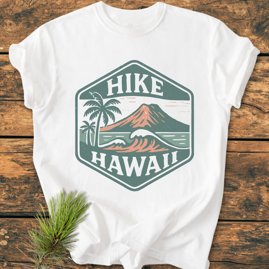 Hike Hawaii - Vintage Wash Tee featuring a hexagon logo with a volcano, waves, and palm trees, laid flat on a wooden surface, ideal for nature enthusiasts and island adventurers.