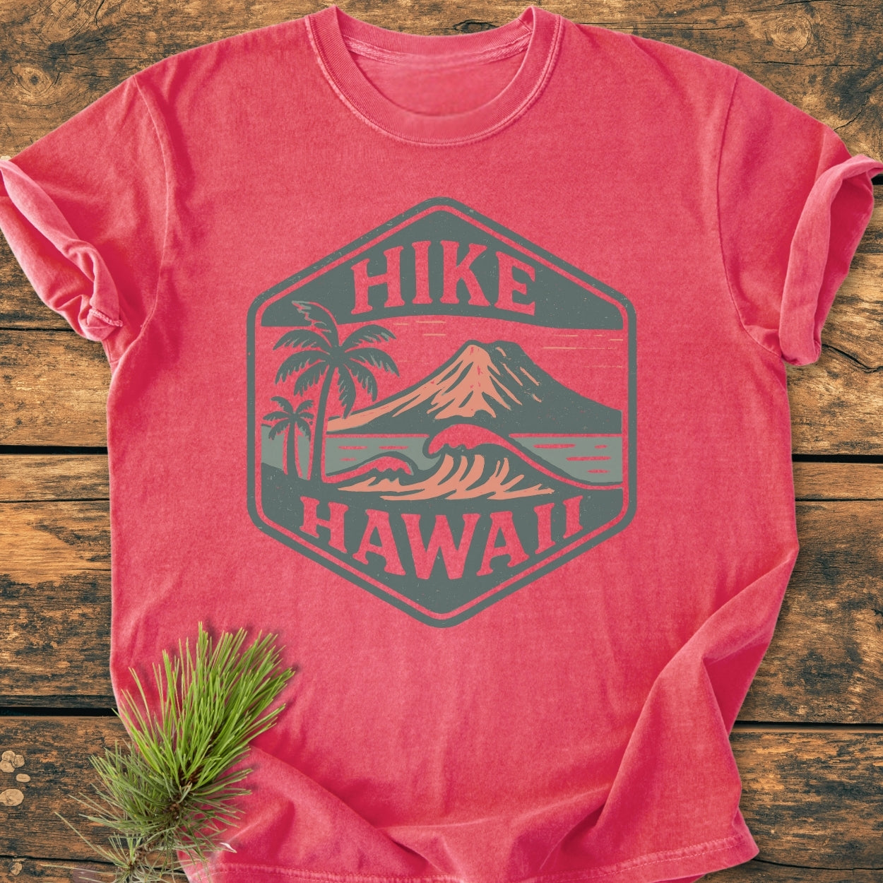 Hike Hawaii - Vintage Wash Tee features a hexagonal badge with palm trees, waves, and a volcano, capturing a tropical adventure spirit on a relaxed fit, reddish-coral T-shirt.