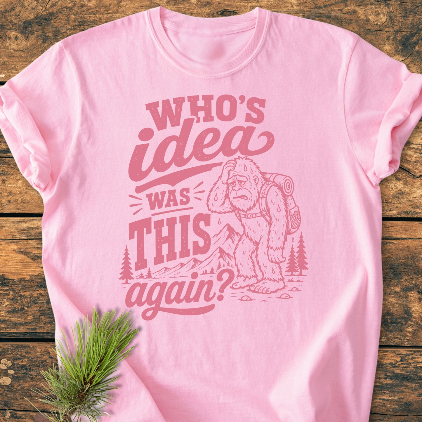 Who's Idea Bigfoot - Vintage Wash Tee featuring a cartoon Bigfoot with a backpack in a mountain scene, humorously questioning hiking decisions. Perfect for adventure lovers with a relaxed, soft fit.