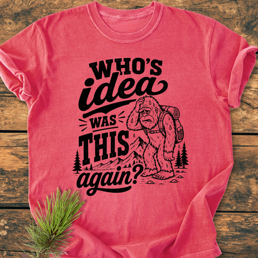 Red T-shirt featuring a black graphic of a tired Bigfoot with a backpack, surrounded by mountains and trees. Bold text reads, “WHO’S idea was THIS again?” Perfect for hikers and adventure lovers.