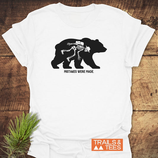 Mistakes Were Made T-Shirt featuring a black bear silhouette with a hiker skeleton graphic, humorous text, and Trails & Tees logo, ideal for adventurers with a taste for dark trail humor.