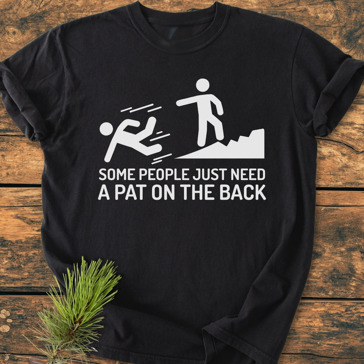 Some People Just Need A Pat On The Back - Vintage Wash Tee featuring stick figures and humorous caption, laid flat on wood, perfect for hikers, crafted from soft, garment-dyed cotton for a relaxed fit.