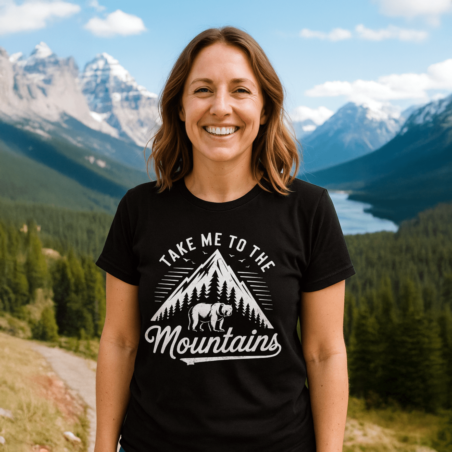 Woman on mountain trail wearing Take Me To The Mountains T-shirt with mountain graphic, designed for comfort and adventure.