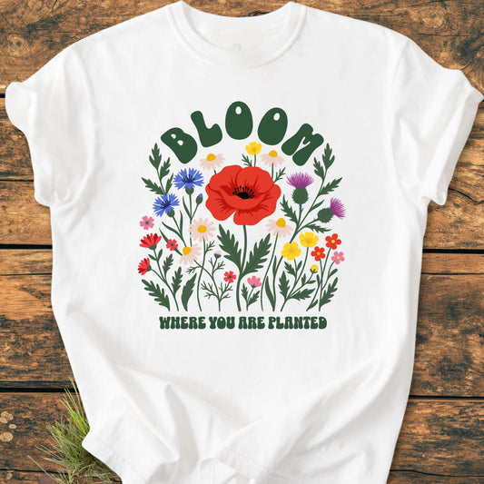 The 1403 Bloom Where You Are Planted Base features a white T-shirt with a vibrant wildflower bouquet and motivational text, offering comfort and style with its relaxed fit and durable ring-spun cotton.