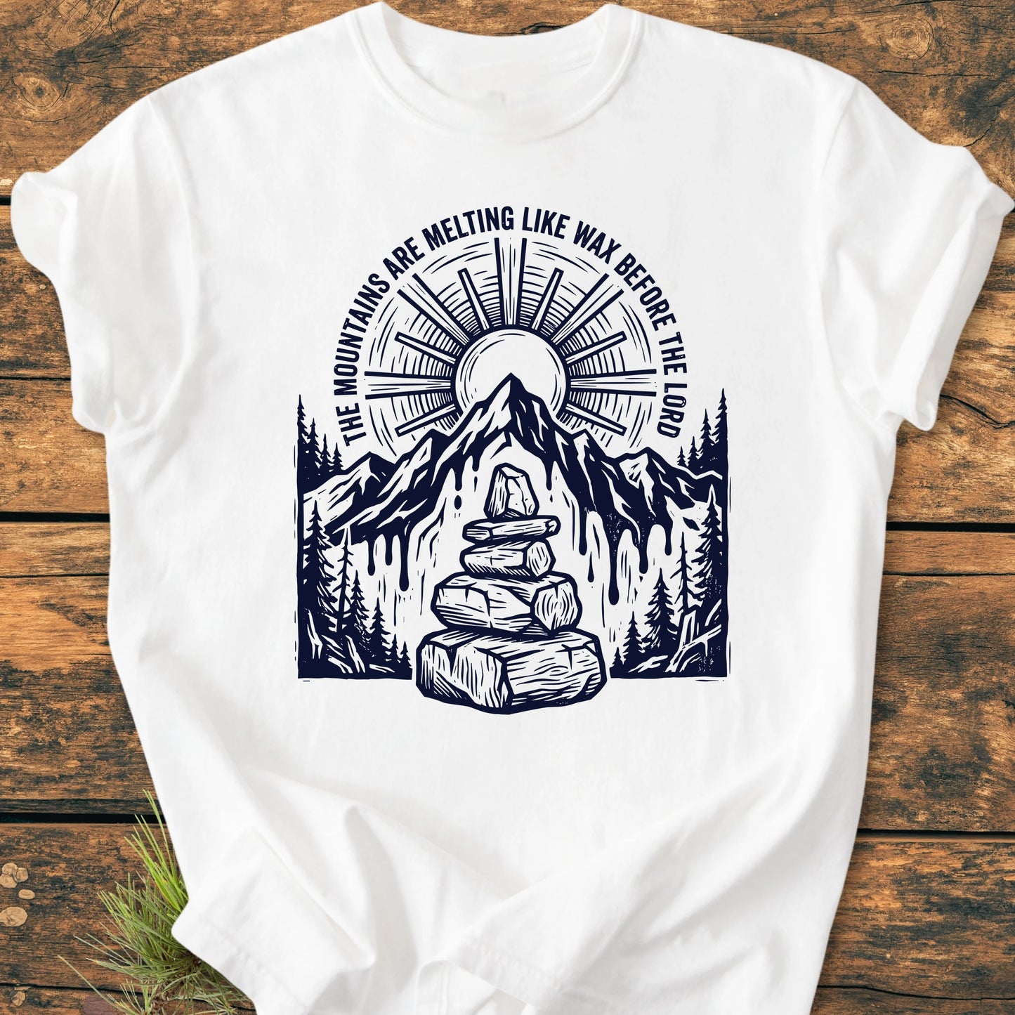 1414 Mountains Melting Like Wax T-shirt features a mountain peak and radiant sun design with pine trees and a cairn, encapsulating an outdoorsy vibe on a vintage wash, soft cotton tee.