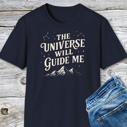 The Universe Guides Me T-Shirt: Navy-blue tee with cream text and stars, made from soft cotton for comfort, accompanied by blue jeans on a wooden surface.