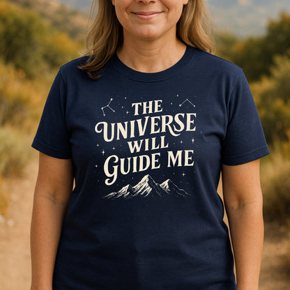 Person wearing The Universe Guides Me T-Shirt on a trail. Features mountain and constellation graphic, crafted from soft cotton for outdoor adventures.