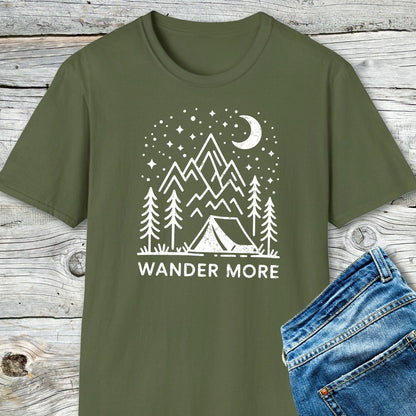 Wander More T-Shirt featuring a camping scene print, laid on wood with jeans; crafted from soft cotton, pre-shrunk, durable, and designed for outdoor enthusiasts.