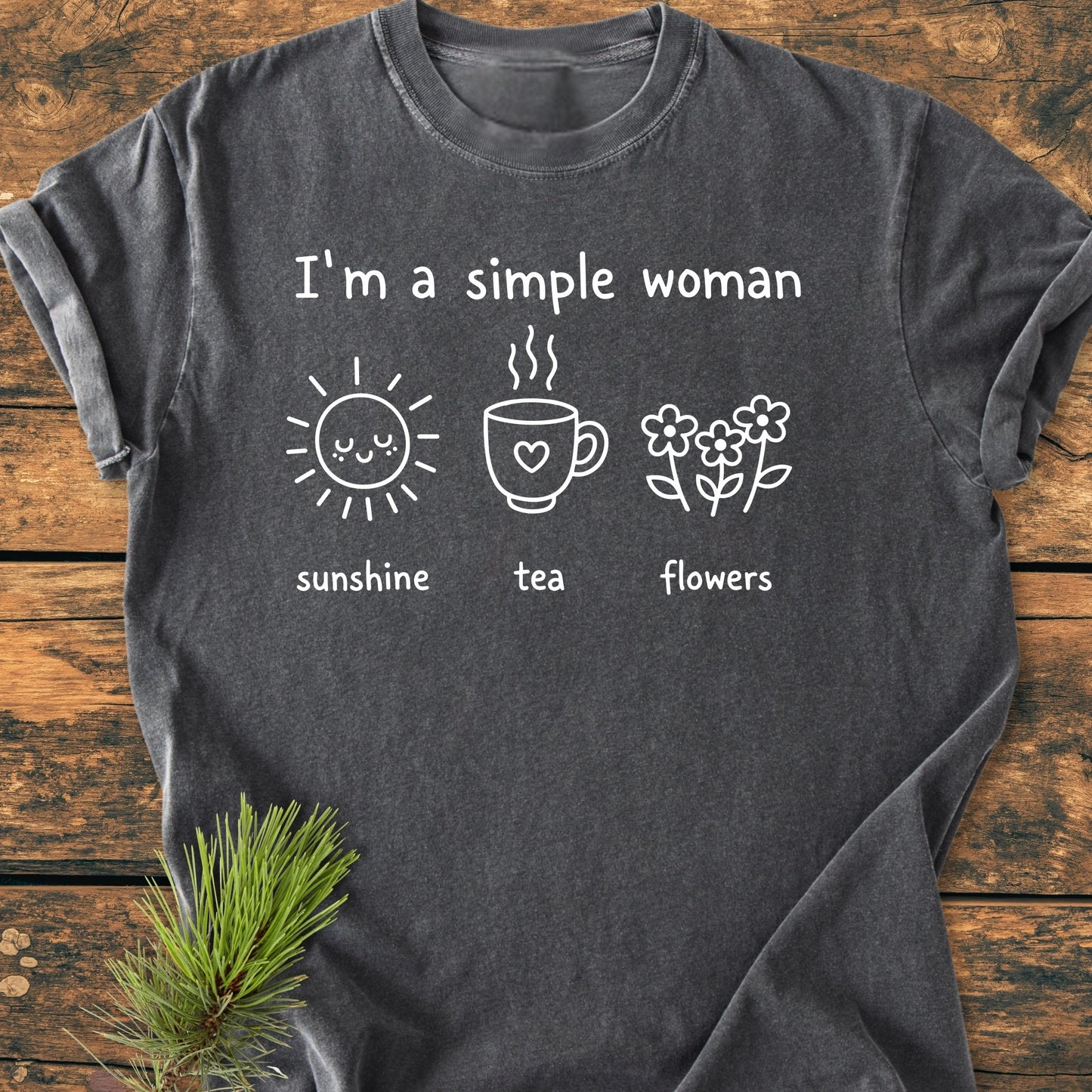 Charcoal-gray T-shirt featuring the phrase “I’m a Simple Woman” with line-drawings of a sun, mug, and flowers. Made from soft-washed, garment-dyed 100% ring-spun cotton for comfort and durability.