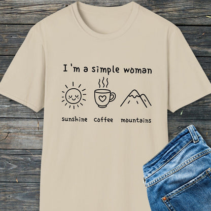 I'm A Simple Woman - Sunshine Coffee Mountains T-Shirt laid flat with blue jeans, displaying icons of a sun, coffee mug, and mountains, emphasizing comfort and simplicity.