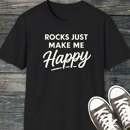 Black Rocks Make Me Happy T-shirt on wood surface, paired with gray sneakers. Lightweight, ring-spun cotton, durable print, pre-shrunk fit.