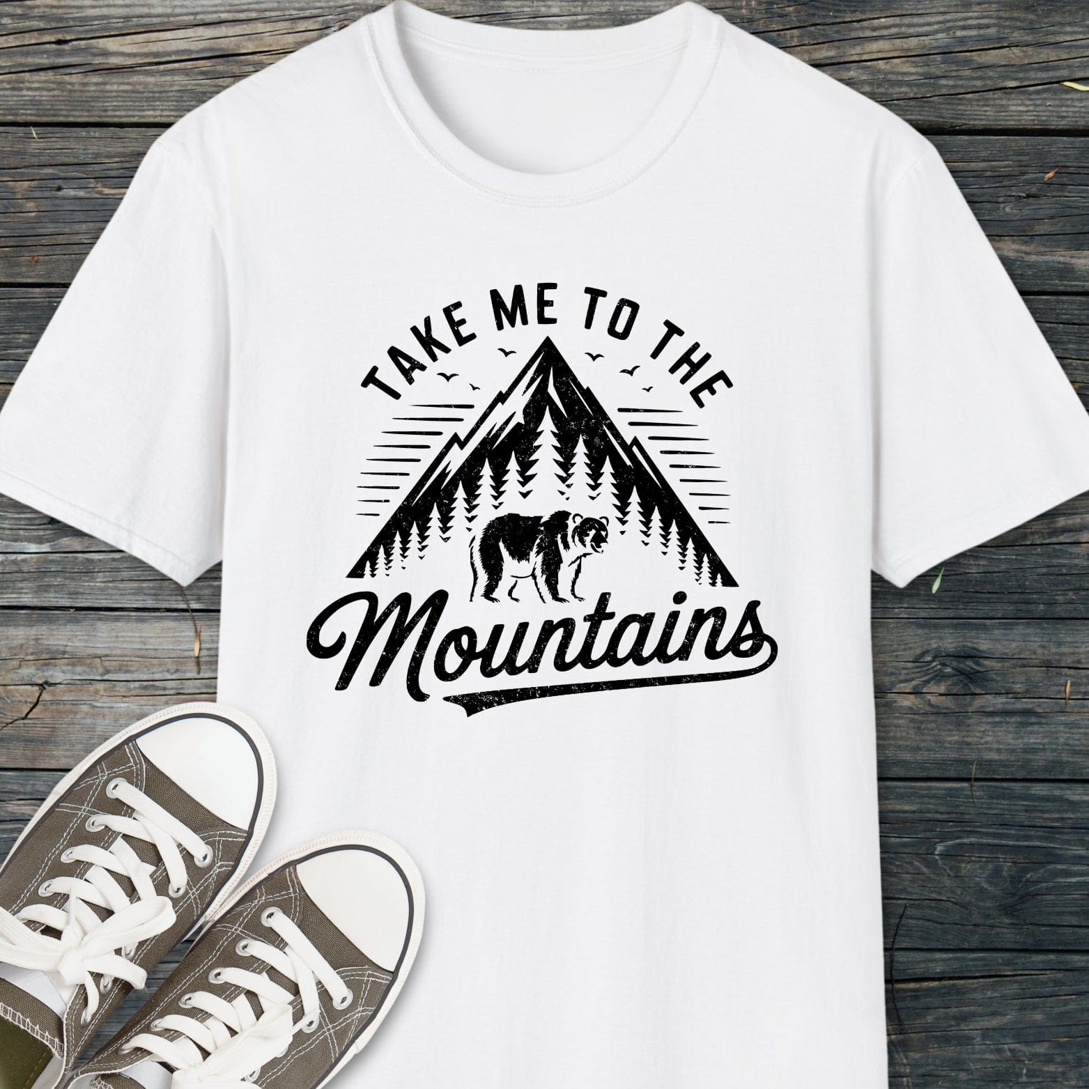 Take Me To The Mountains T-Shirt with a graphic of a mountain and bear, designed for comfort and adventure, paired with casual canvas sneakers.