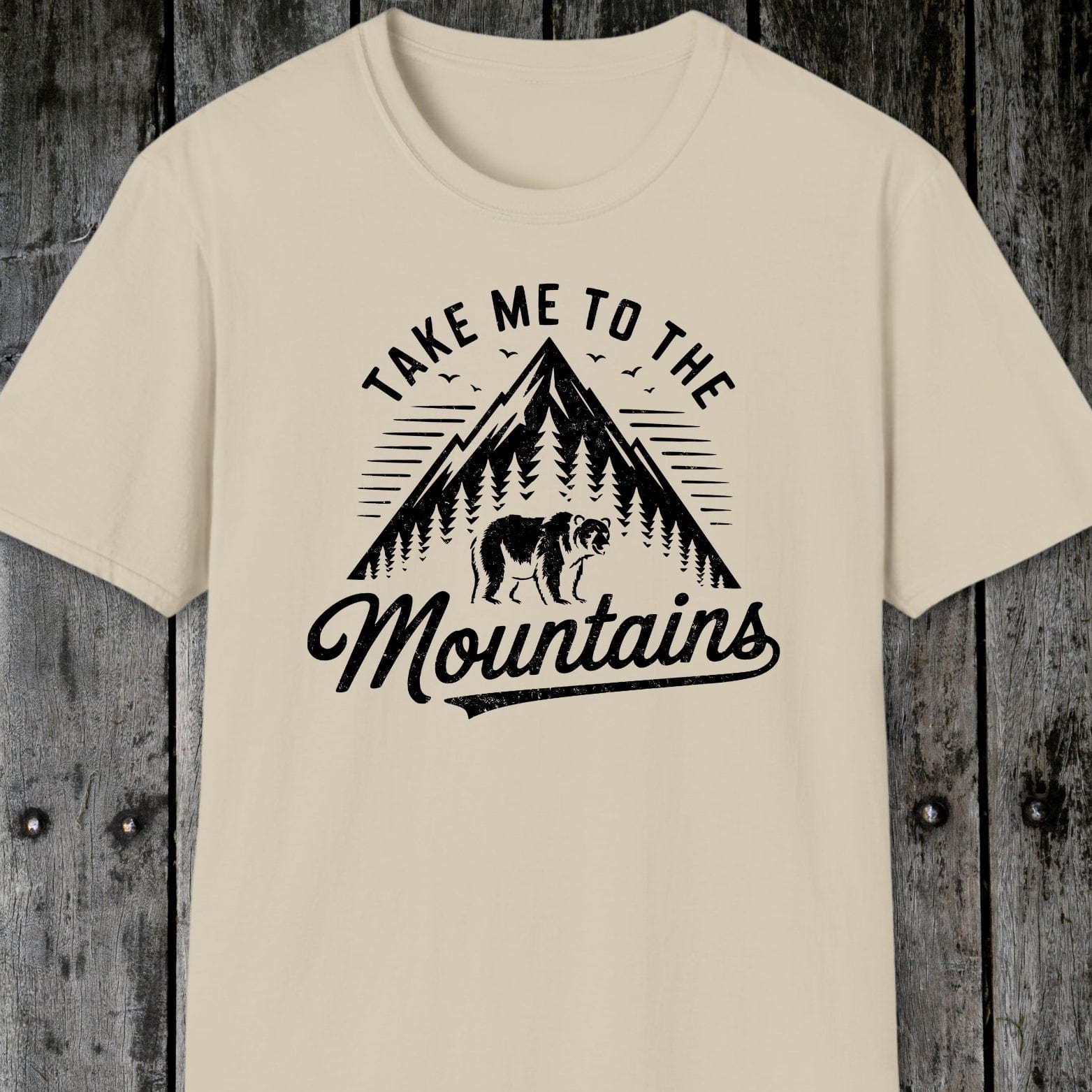 Take Me To The Mountains T-Shirt featuring a vintage-style mountain graphic with a bear, birds, and sun-ray lines. Soft, lightweight cotton ideal for adventures.