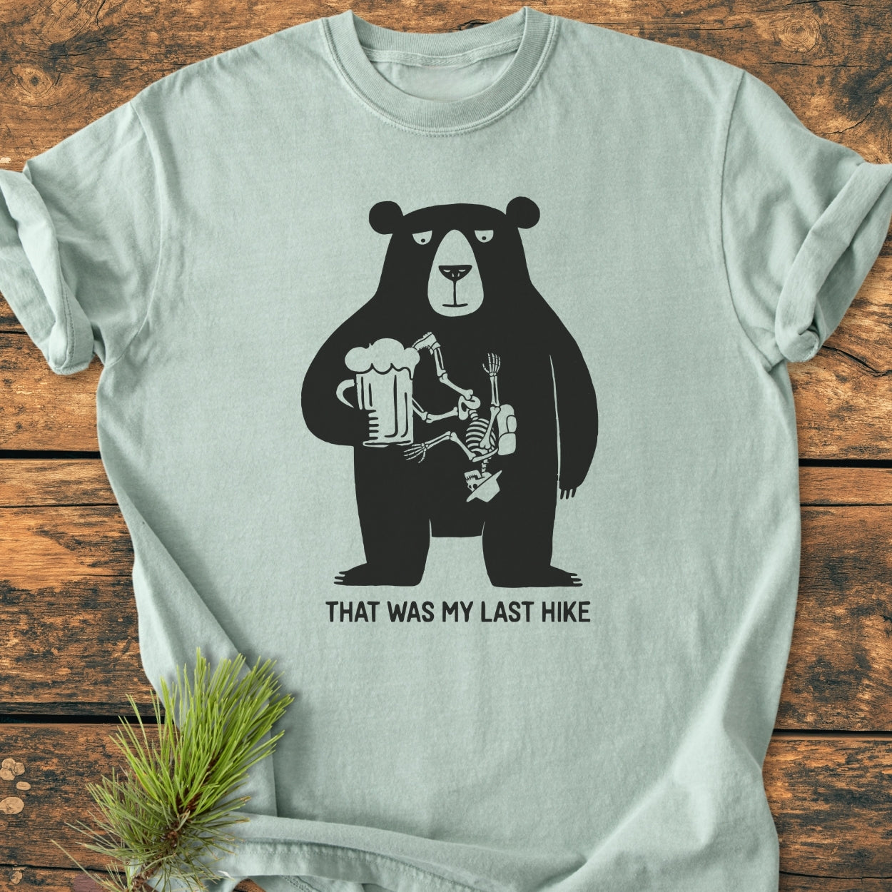 That Was My Last Hike - Vintage Wash Tee features a bear with a beer mug and skeleton graphic, emphasizing comfort with its garment-dyed, soft-washed fabric and relaxed fit for everyday wear.