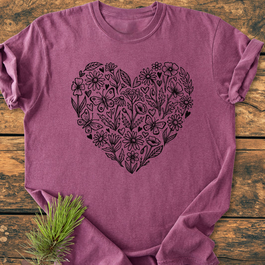 Wildflower Heart Butterfly Soul - Vintage Heavyweight Tee features a black line-art heart with flowers, leaves, and butterflies on a soft, heathered-raspberry T-shirt, laid on a rustic wooden surface.