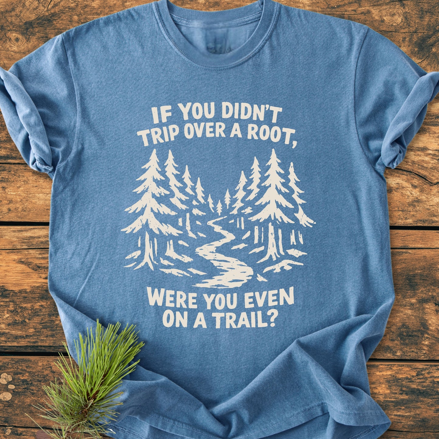 Were You Even On A Trail? - Vintage Wash Tee features a stylized forest scene with pine trees and trail, printed in off-white on a heather-blue T-shirt, complemented by a sprig of pine needles.
