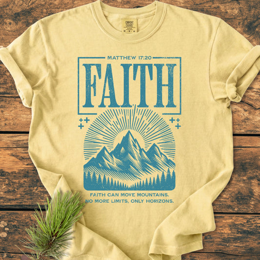 Faith Moves Mountains - Vintage Wash Tee features Faith and Matthew 17:20 in distressed sky-blue ink, with sun-rays and mountains graphic, laid on wood with pine sprig. Soft, relaxed fit.