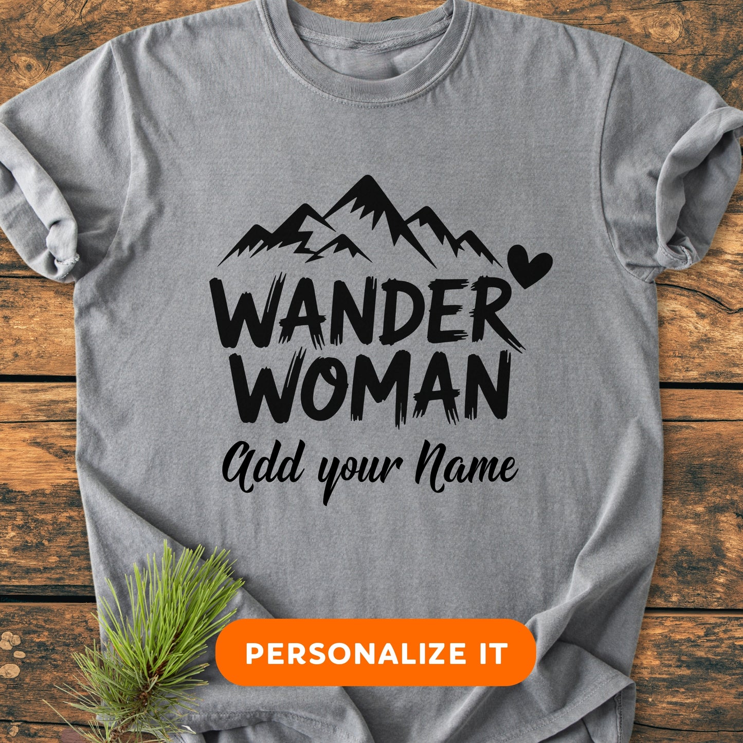 Wander Woman | Custom Name | Vintage Wash Tee featuring black mountain graphics, “WANDER WOMAN”, and “Add your Name” text on a light-gray T-shirt, laid flat with a rustic pine sprig accent.