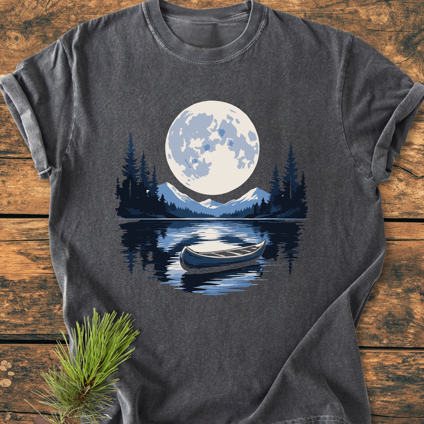 Moonlit Canoe - Vintage Wash Tee featuring a nighttime scene with a full moon, drifting canoe, and snow-topped mountains, all printed on a dark-gray, short-sleeve T-shirt laid flat.