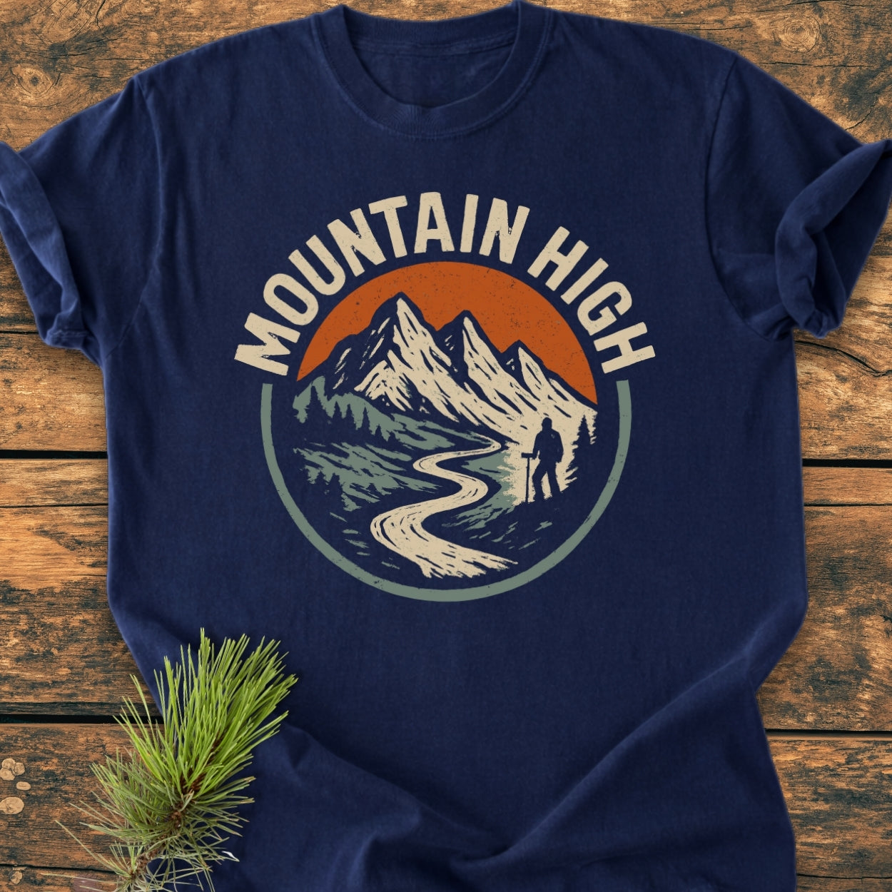 Mountain High - Vintage Wash Tee: Navy-blue T-shirt features a mountain graphic with a hiker and MOUNTAIN HIGH text, laid on wood. Soft, durable, relaxed fit, 100% ring-spun cotton.