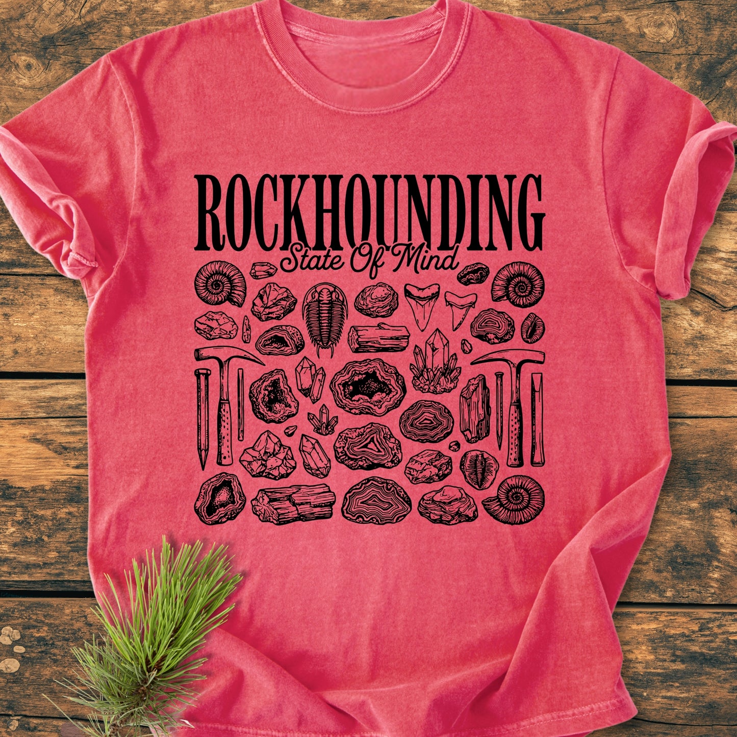 Rockhounding State Of Mind - Vintage Wash Tee features black graphics of rocks and tools on a pink tee, laid flat. Made from soft, ring-spun cotton, offering comfort and durability.