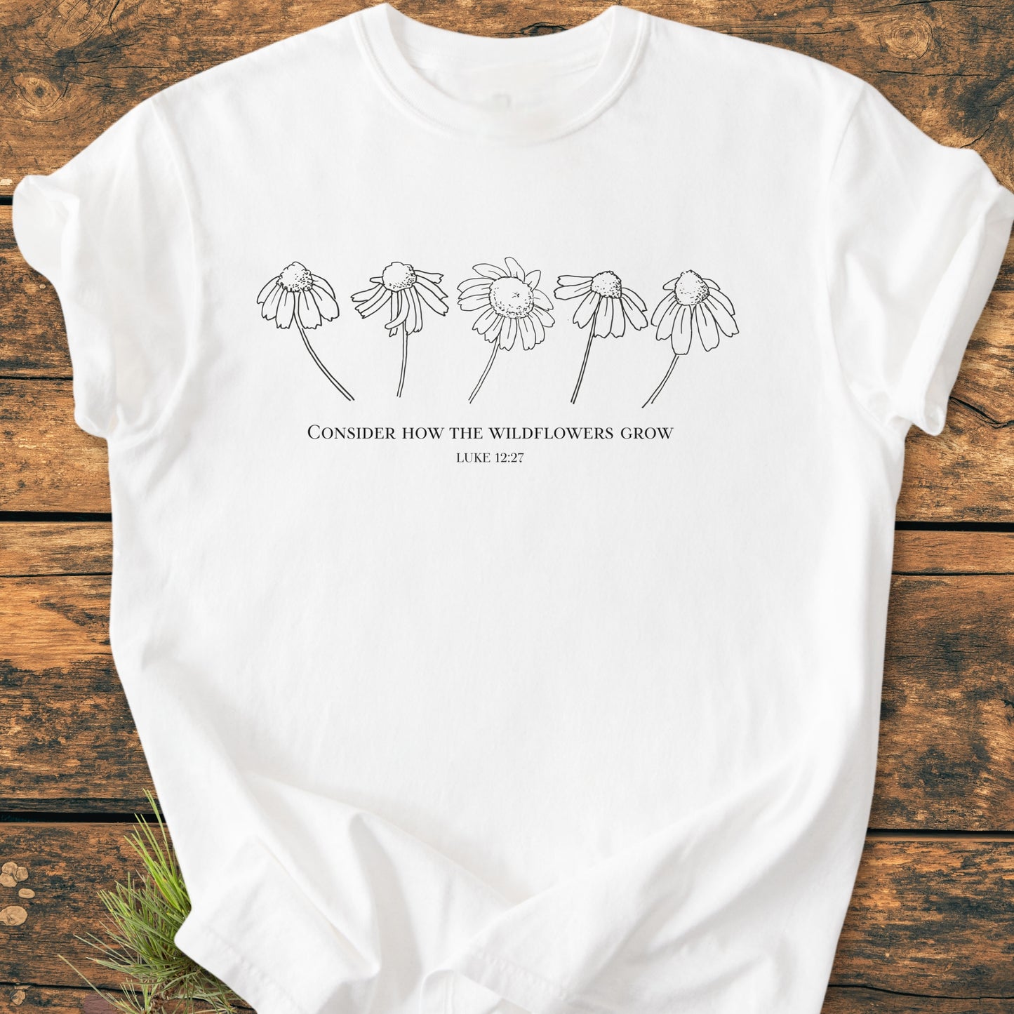 Consider How The Wildflowers Grow - Vintage Wash Tee features a minimalist design with five wildflowers and a Bible verse on a soft, white T-shirt, laid flat showcasing its relaxed fit.