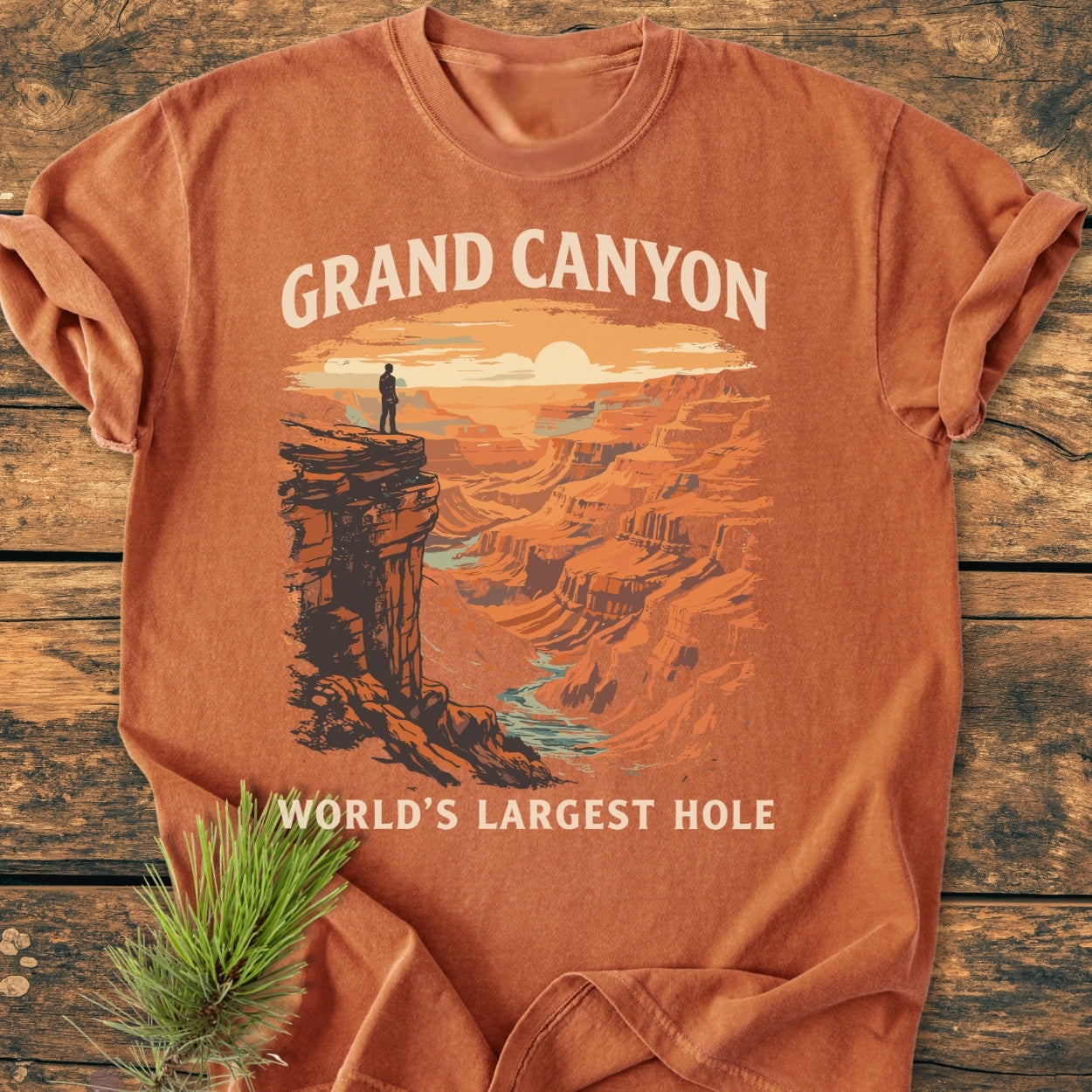 Grand Canyon Large Hole - Vintage Wash Tee displayed on wood, featuring a Grand Canyon illustration and text. Soft, relaxed fit, garment-dyed, durable ring-spun cotton, evoking nature with a pine sprig accent.