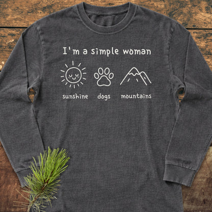 I'm A Simple Woman - Sunshine, Dogs, Mountains Long-Sleeve Tee featuring white lettering and icons on a dark-gray shirt, laid flat with a pine branch accent, emphasizing casual comfort and personalized style.
