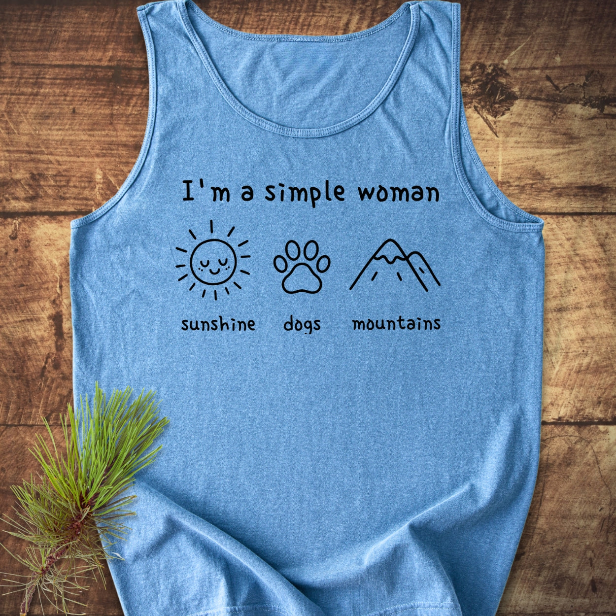 I'm A Simple Woman - Sunshine, Dogs, Mountains Tank Top features a heather-blue design with black text and line drawings of a sun, paw print, and mountains, emphasizing comfort, style, and sustainability.