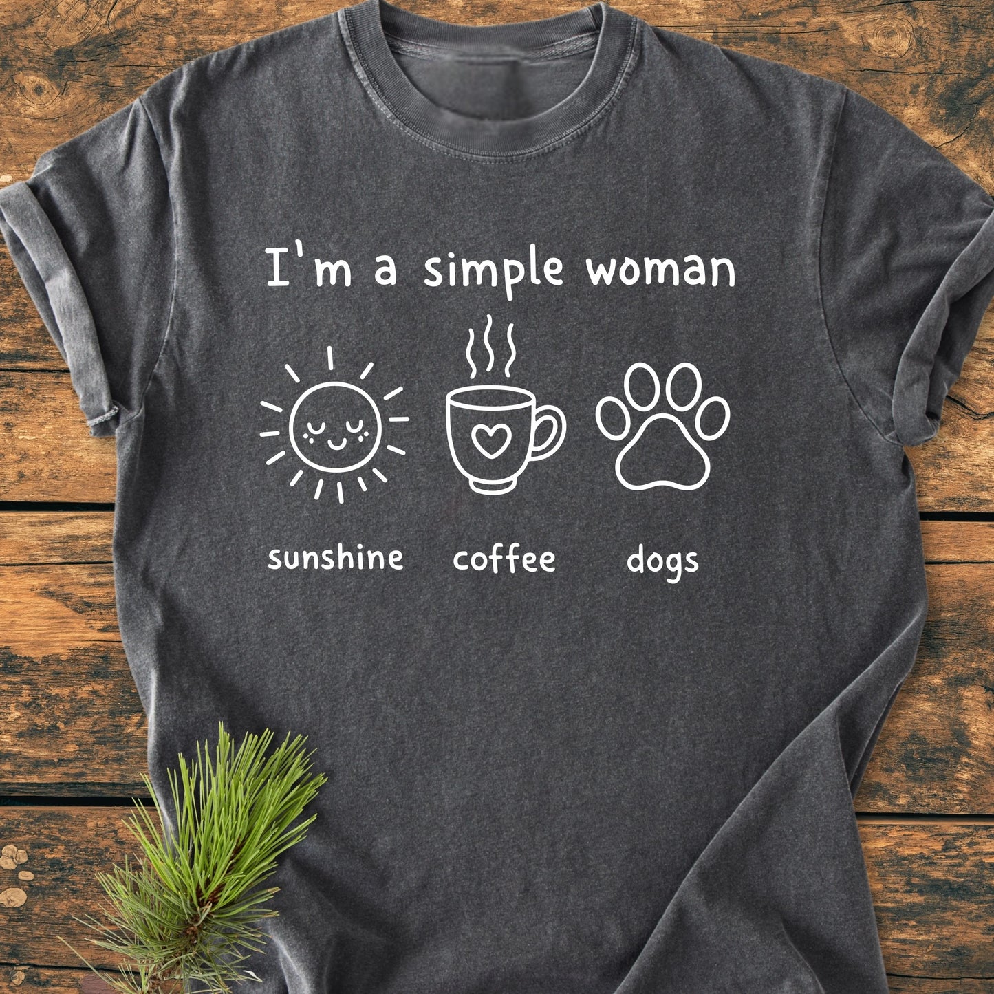 I'm A Simple Woman. Sunshine Coffee Dogs - Vintage Wash Tee, featuring white text and icons of a sun, coffee mug, and dog paw, laid out on a wooden surface.