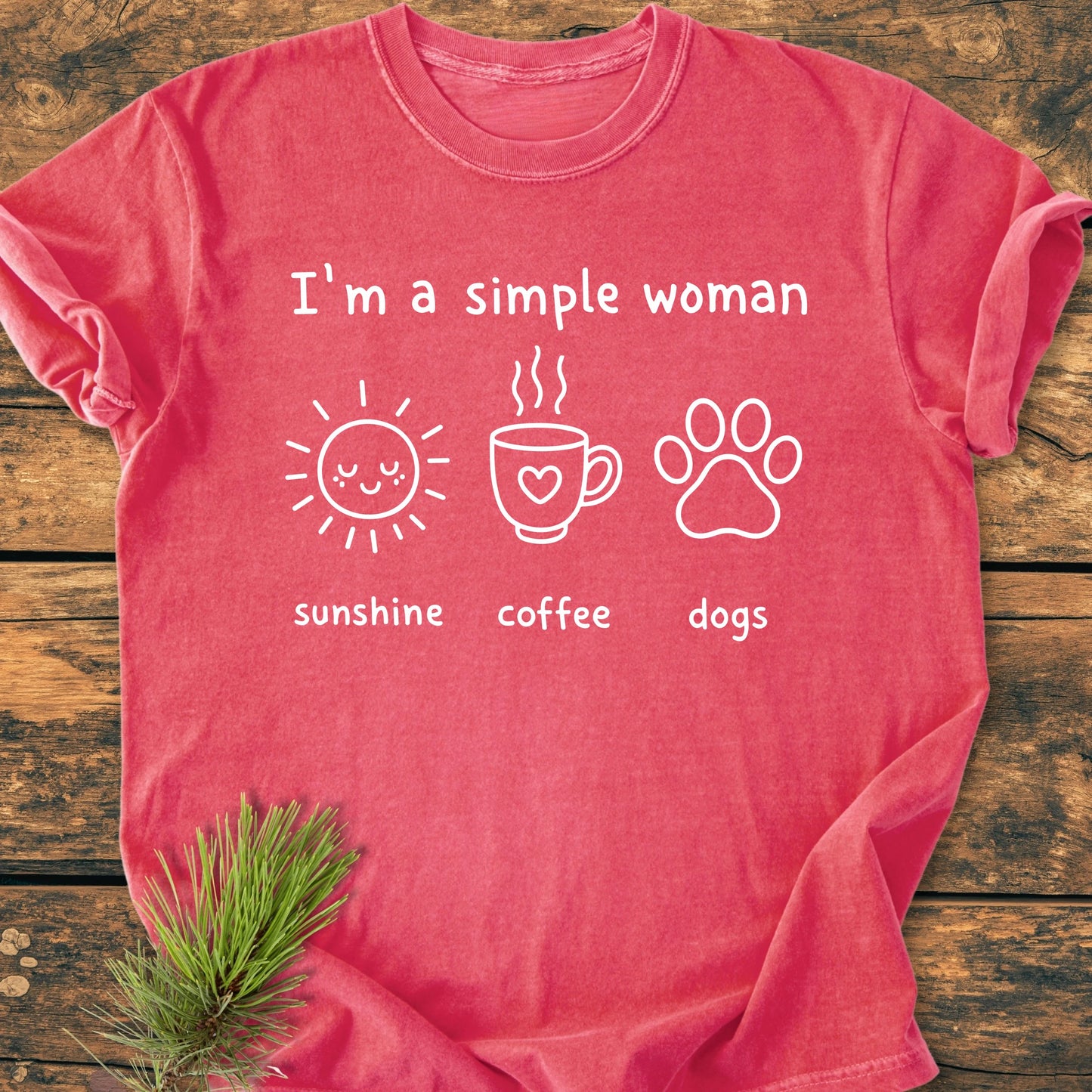 I'm A Simple Woman. Sunshine Coffee Dogs - Vintage Wash Tee features white text and icons on a red-coral T-shirt, laid flat on wood, embodying a relaxed, unisex fit with a lived-in feel.