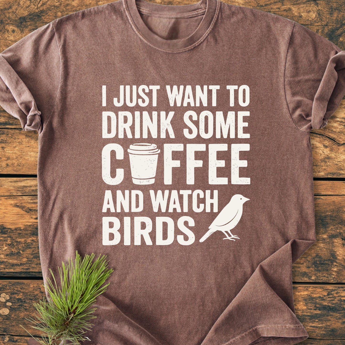 Brown T-shirt in a flat-lay with 1405 Drink Coffee And Watch Birds Base slogan featuring a coffee cup icon and bird silhouette, highlighting comfort and durability.
