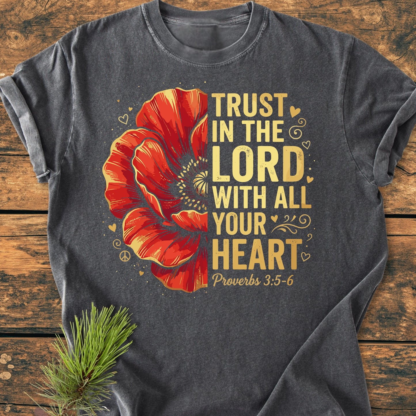 Trust In The Lord - Vintage Wash Tee features a large red flower, gold-yellow Proverbs 3:5–6 quote, hearts, swirls, and peace symbol on a charcoal-gray T-shirt, accented by an evergreen sprig.