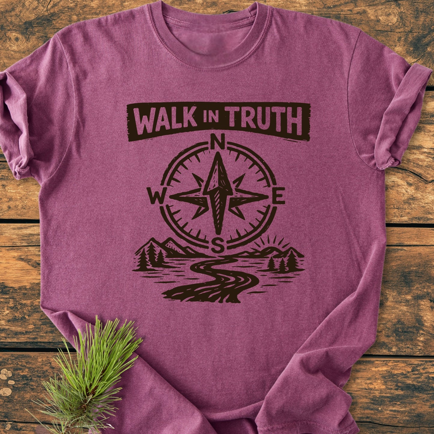 Walk In Truth 3 John 1,4 - Vintage Wash Tee featuring a compass rose, path, and mountain scene printed on a heather-purple shirt, displayed flat with a pine sprig beside it.