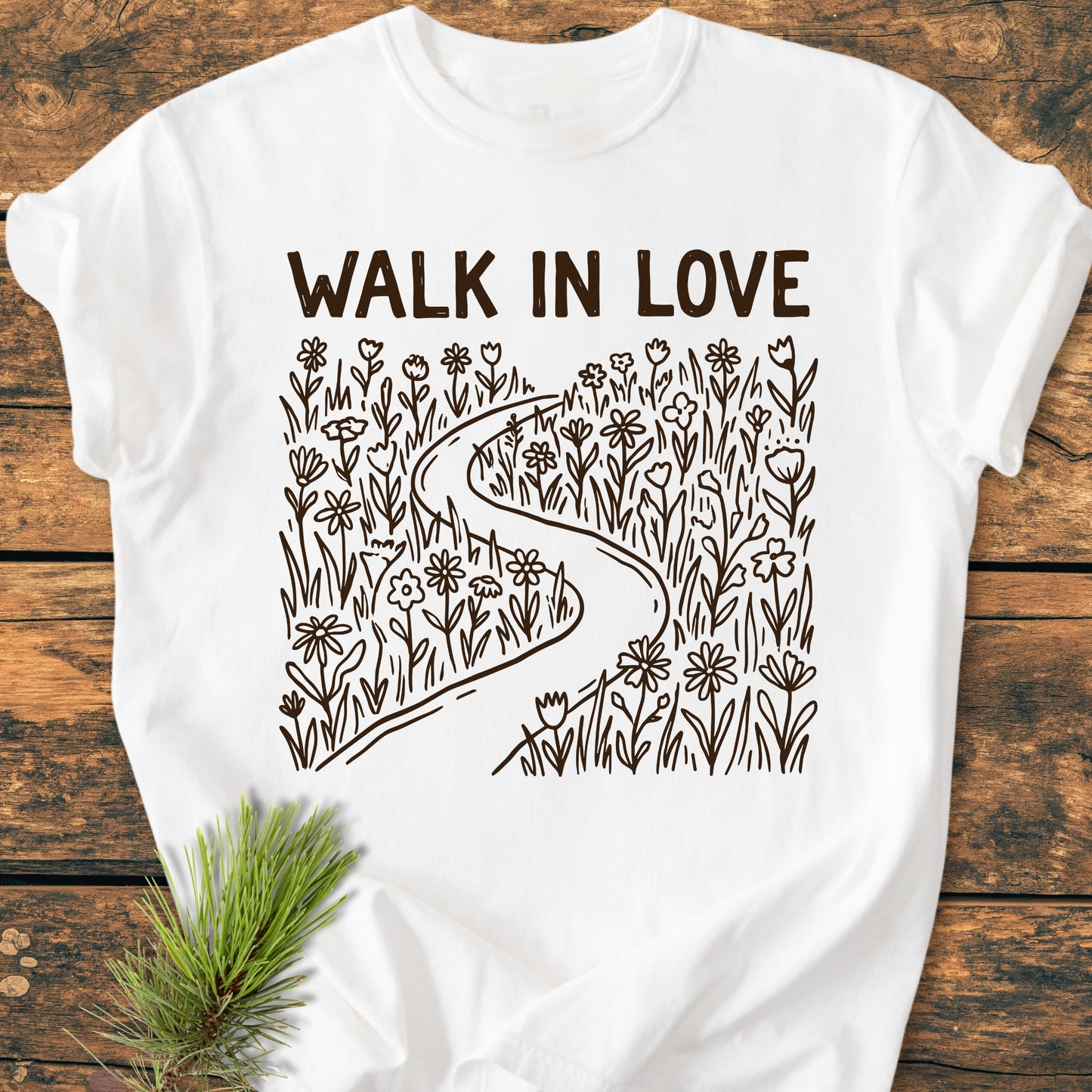 Walk In Love - Vintage Wash Tee featuring a WALK IN LOVE print with a path through wildflowers, styled with an evergreen sprig, showcasing a soft, relaxed fit made of cozy garment-dyed cotton.
