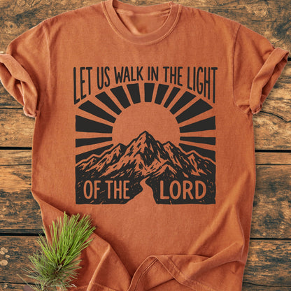 The Let Us Walk In The Light Of The Lord - Vintage Wash Tee features a mountain range and sunbeams graphic, emphasizing faith and nature, on a burnt-orange, soft-washed, ring-spun cotton T-shirt.
