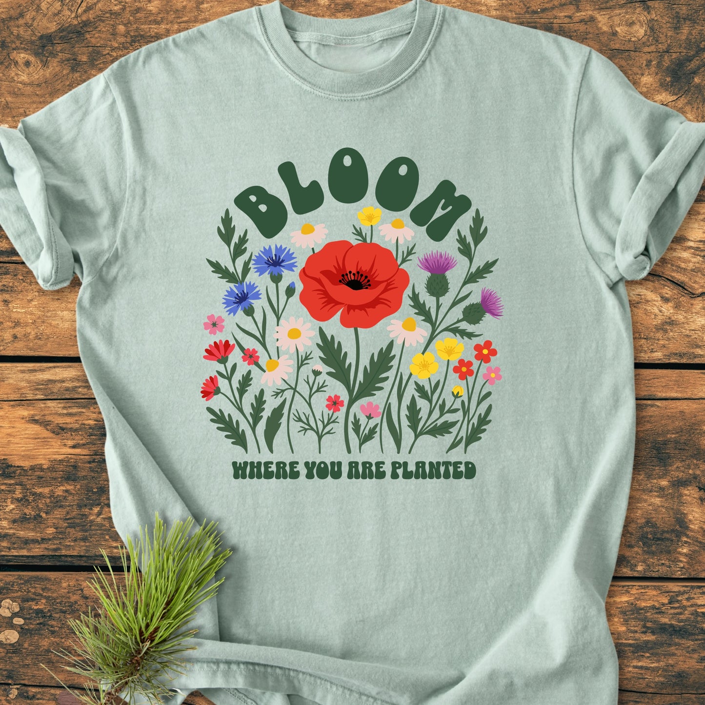 1403 Bloom Where You Are Planted Base T-shirt features 'BLOOM' and wildflowers print on seafoam fabric, offering a relaxed fit with durable, soft-washed garment-dyed 100% ring-spun cotton.